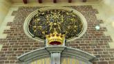 Über dem Eingang prangt das verschnörkelte Wappen Mariens.